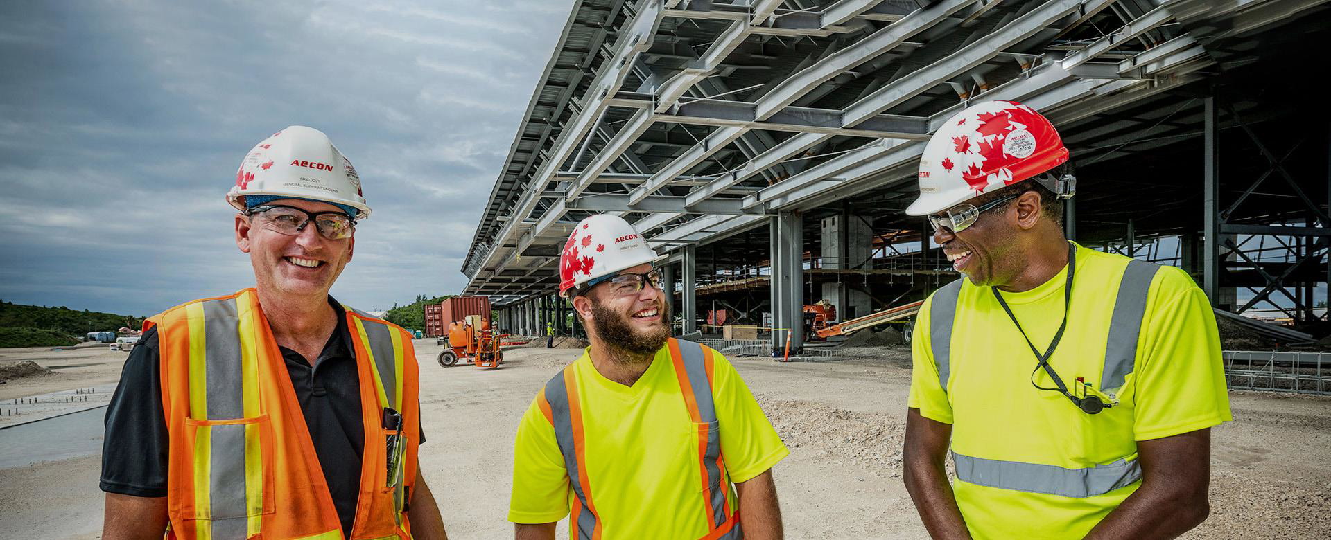 Three construction professionals smiling in hardhats